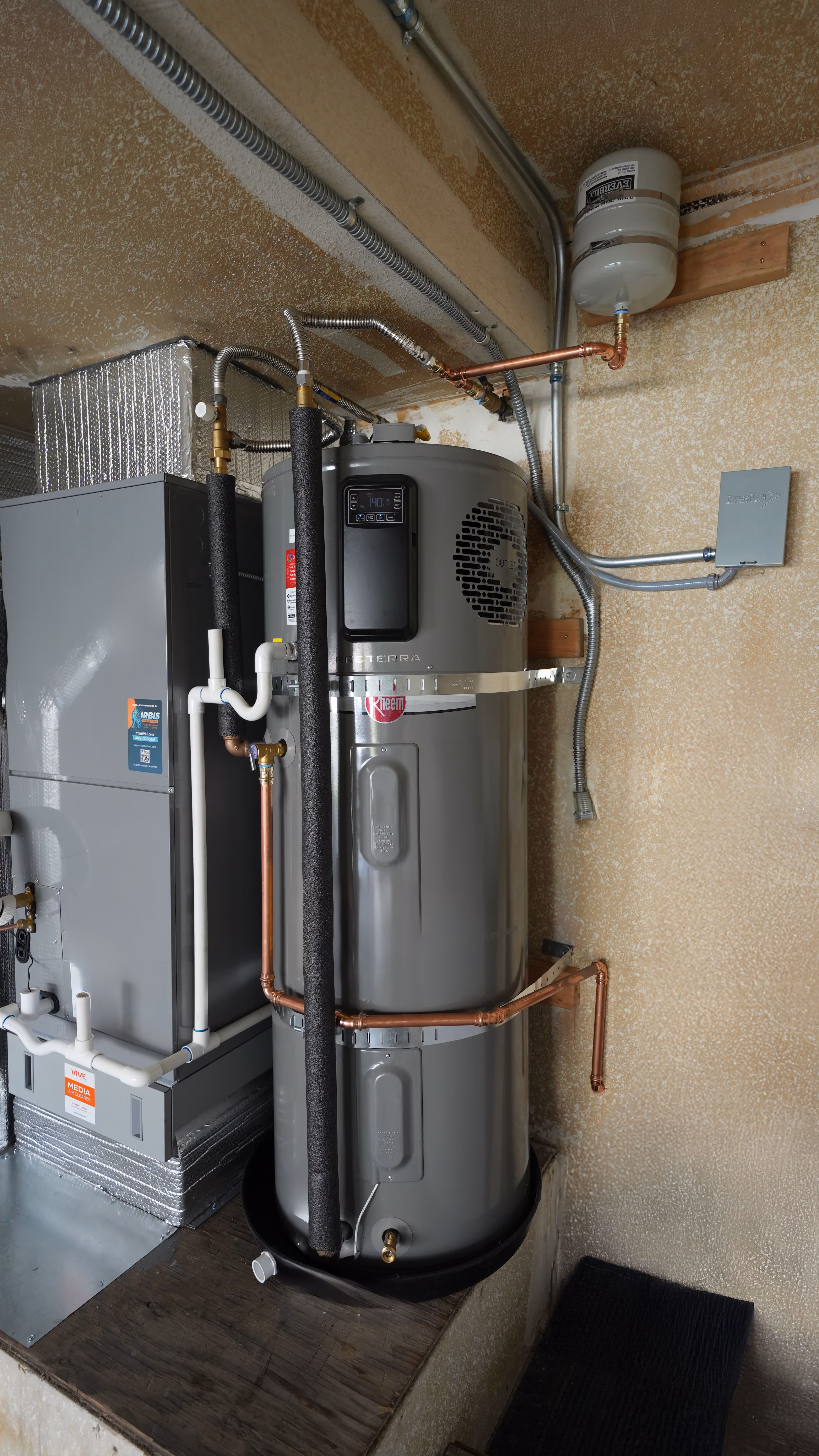 A Rheem ProTerra gray water heater with insulation and copper piping installed next to HVAC ductwork in a utility room.