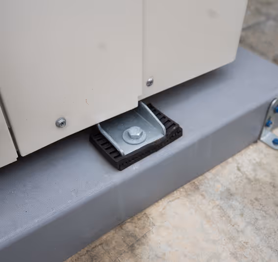 Metal bracket with bolt attached to a beige panel on a gray concrete surface.