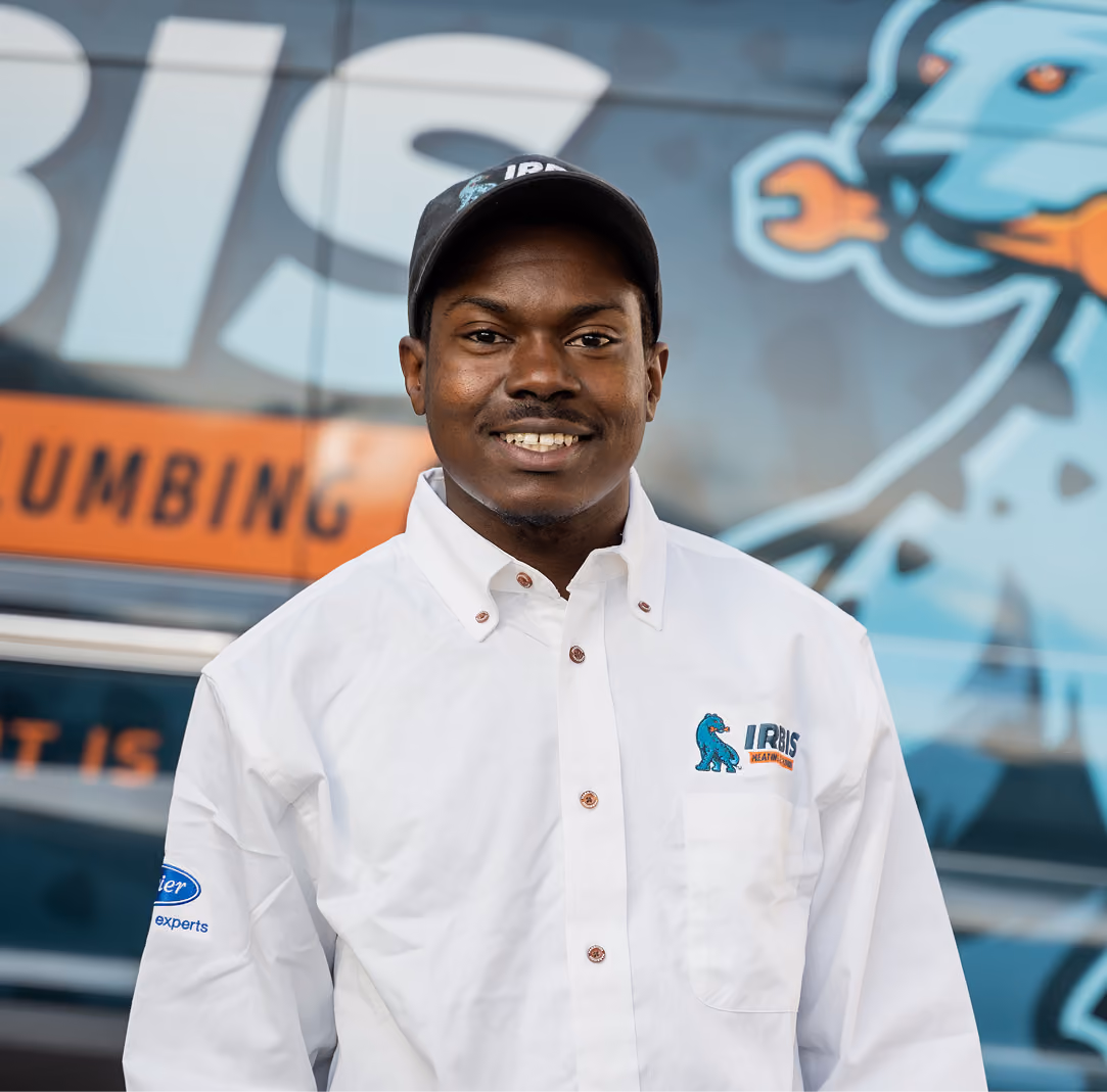 Smiling man in white shirt and cap with Irbis Heating logo stands in front of a branded vehicle.