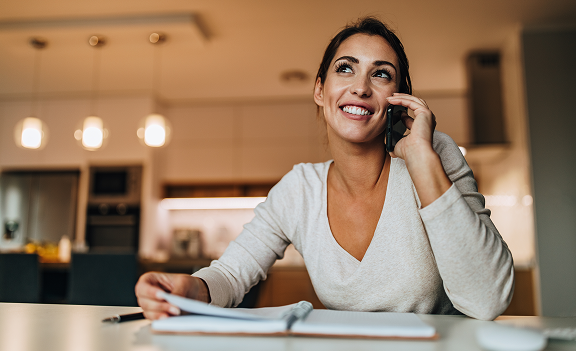 A woman on the phone looking through a notebook