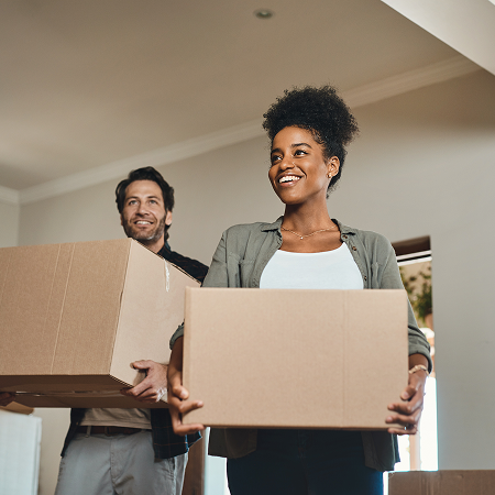 Couple carrying boxes into new home.
