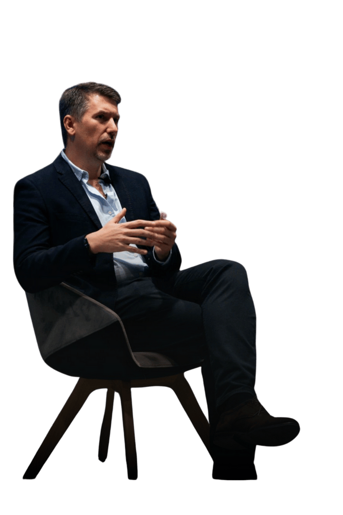 Dr Paweł Kowalski siedzi na krześle, gestykulując podczas merytorycznej dyskusji o wdrożeniach sztucznej inteligencji