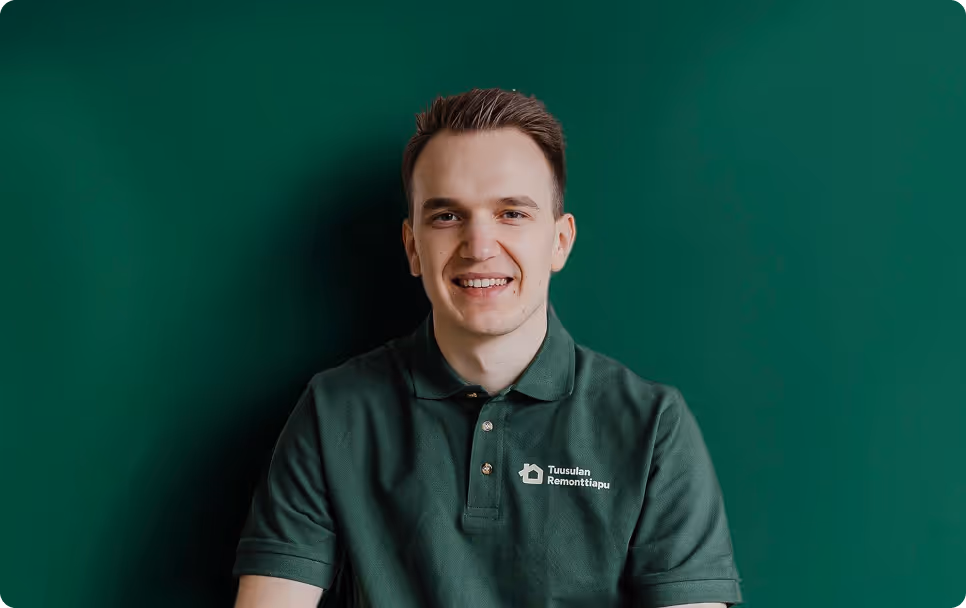 Smiling young man wearing a dark green polo shirt with Tuusulan Remonttiapu logo on a matching green background.