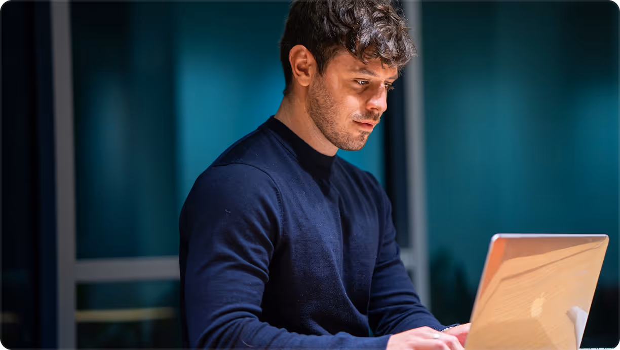 Kaksi hymyilevää miestä seisoo sisätiloissa, toinen pitelee kannettavaa tietokonetta ja toisella Jotform-mukia.