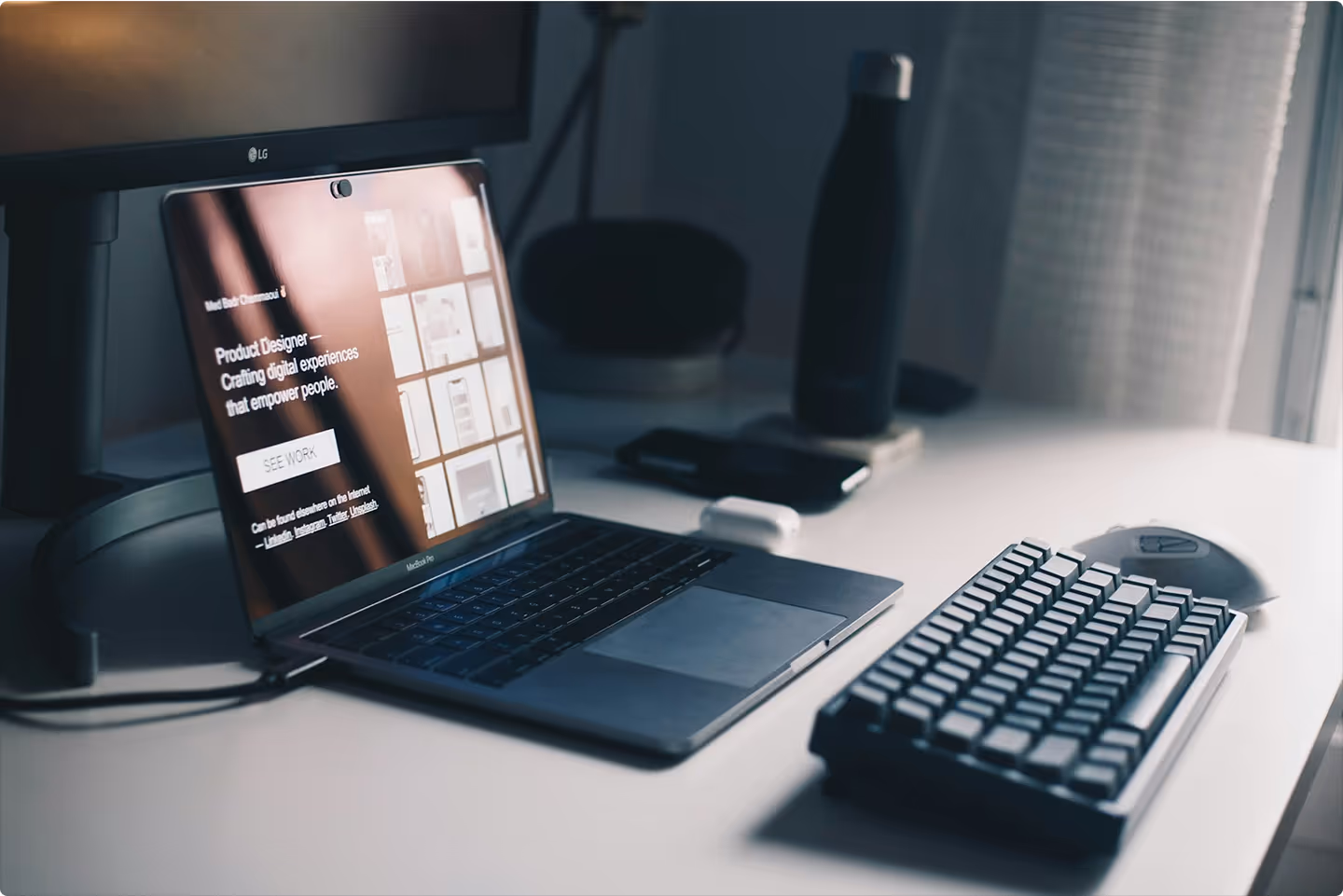 Laptop on a desk displaying a digital product designer portfolio alongside a mechanical keyboard and mouse.