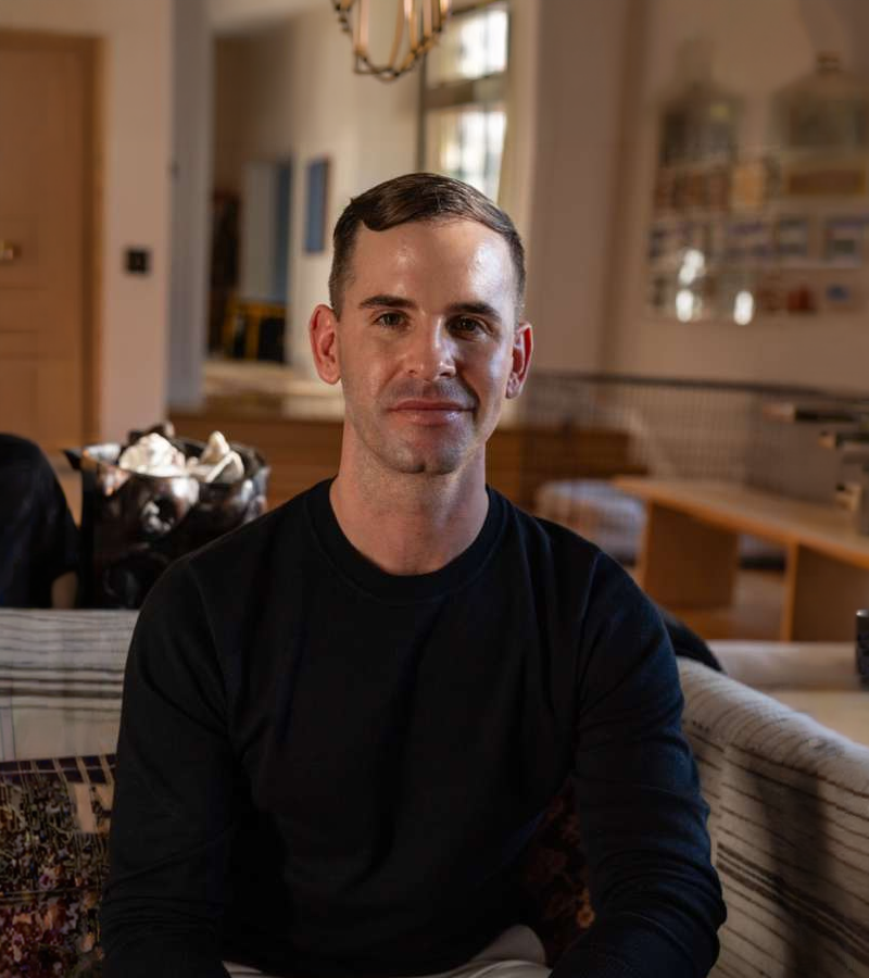 Smiling young man wearing a dark green polo shirt with Tuusulan Remonttiapu logo on a matching green background.