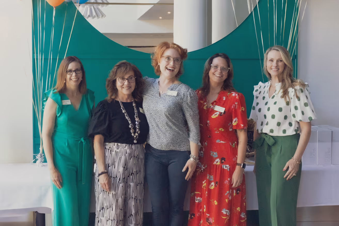 A photo of CoSpire Consulting team members. They stand together and are joyfully posing, with arms around one another.