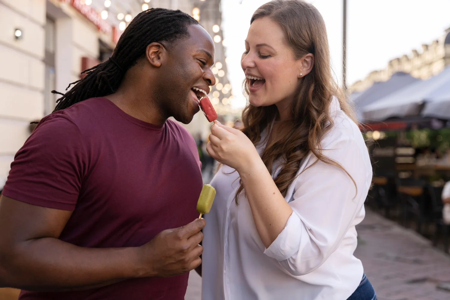 A man and a woman are laughing and eating food.