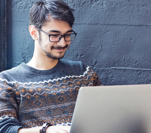 a man wearing glasses using a laptop computer