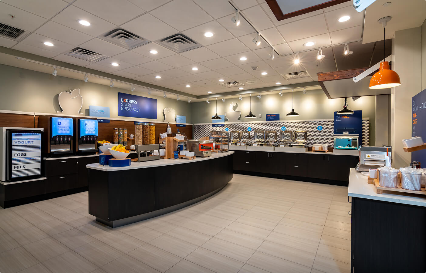 Modern breakfast buffet setup with cereal dispensers, fruit bowls, hot food trays, and beverage machines.