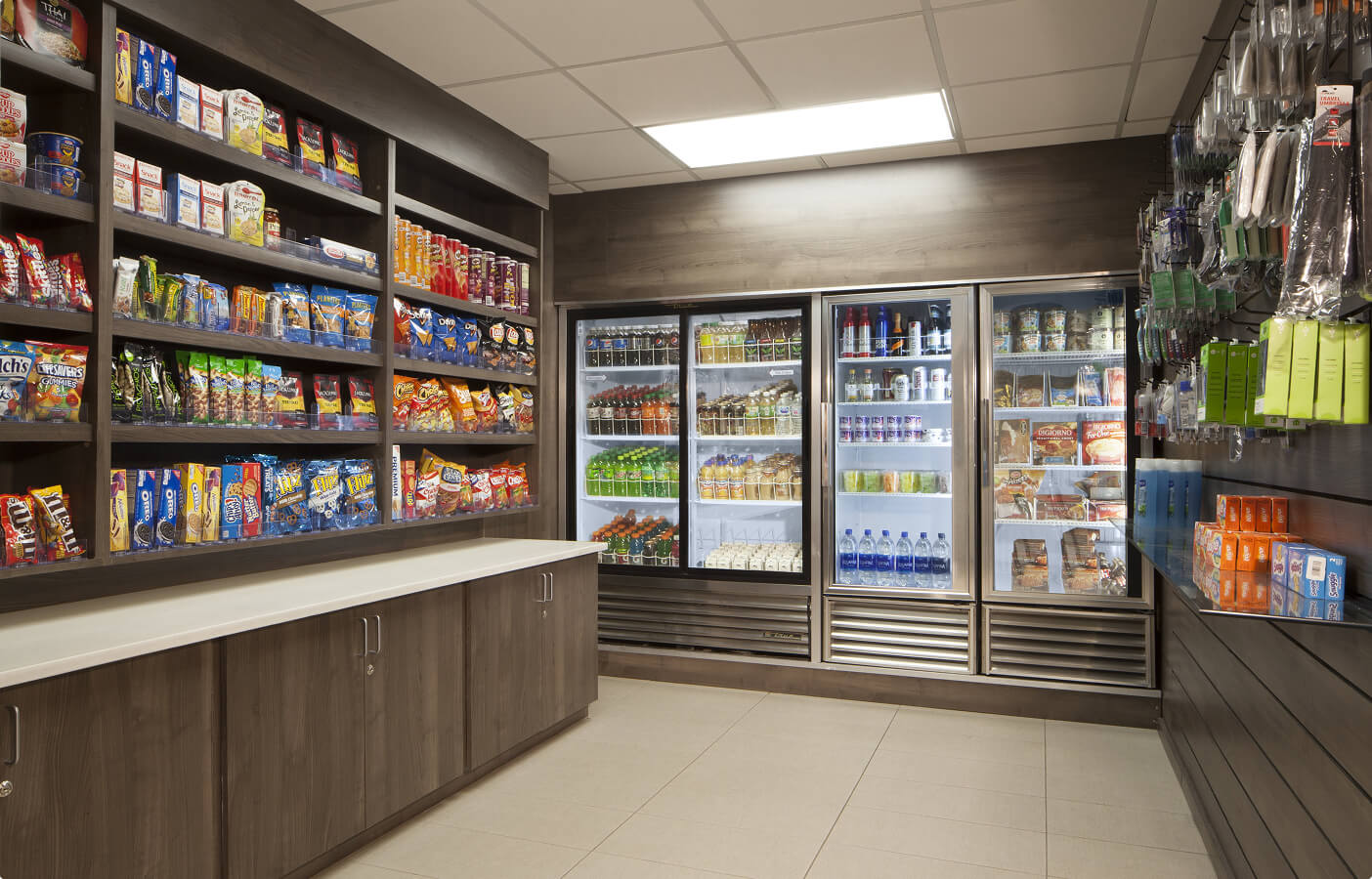 Convenience store corner with shelves of snacks and refrigerators stocked with drinks and food items.