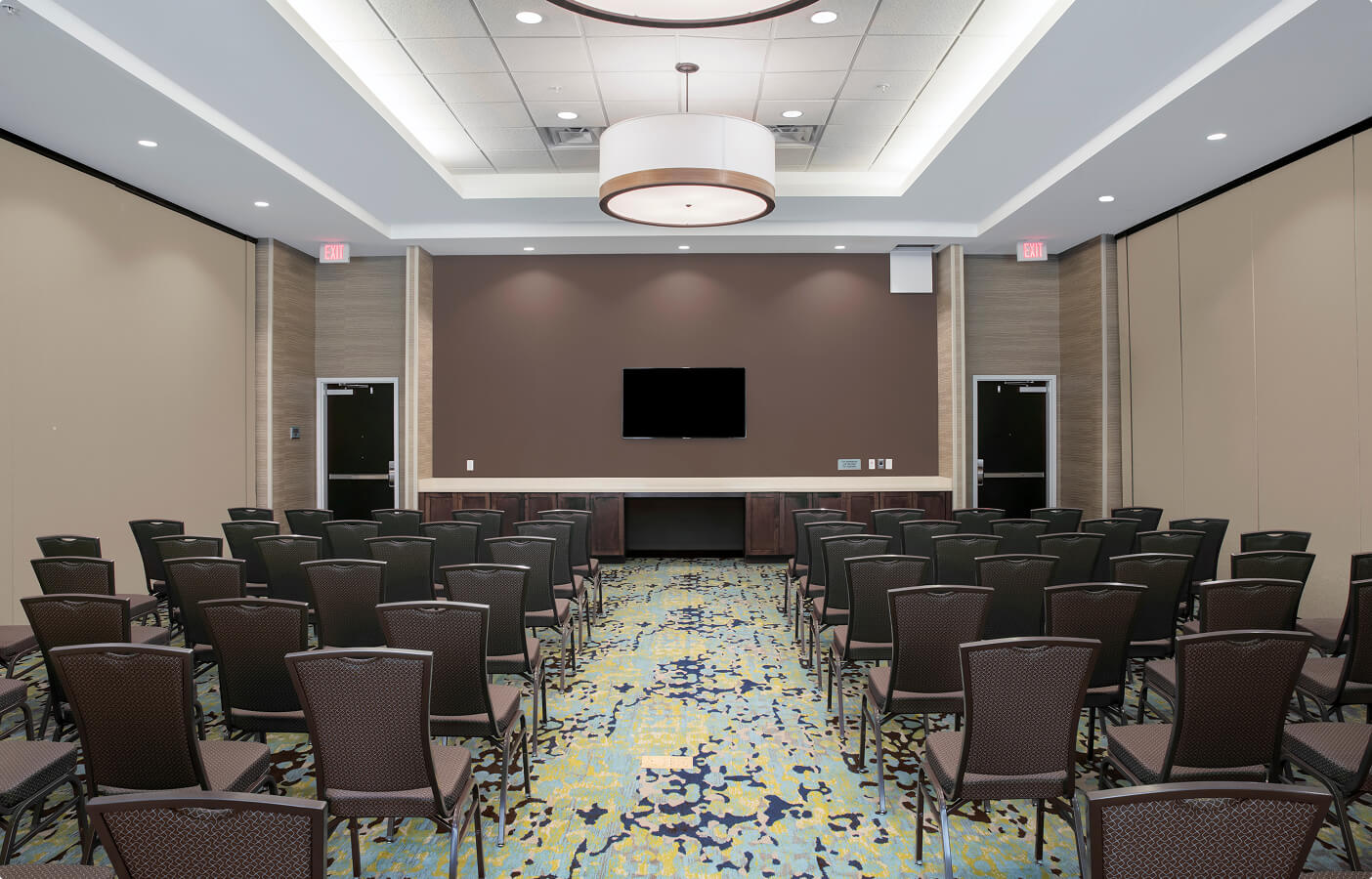 Modern conference room with rows of empty chairs facing a blank wall-mounted TV.