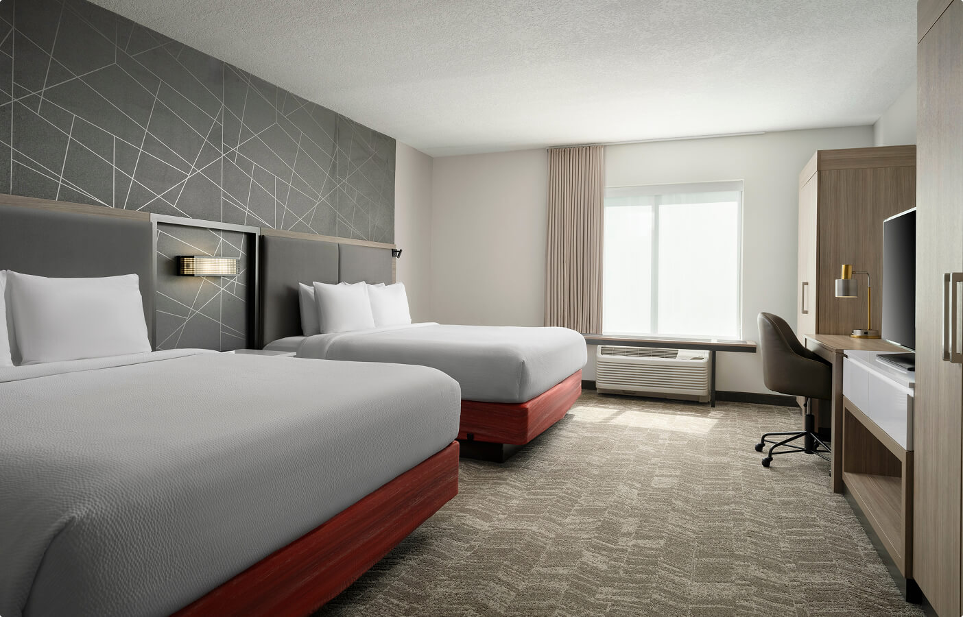 Hotel room with two queen beds, a desk with chair, a TV, and a large window with curtains.