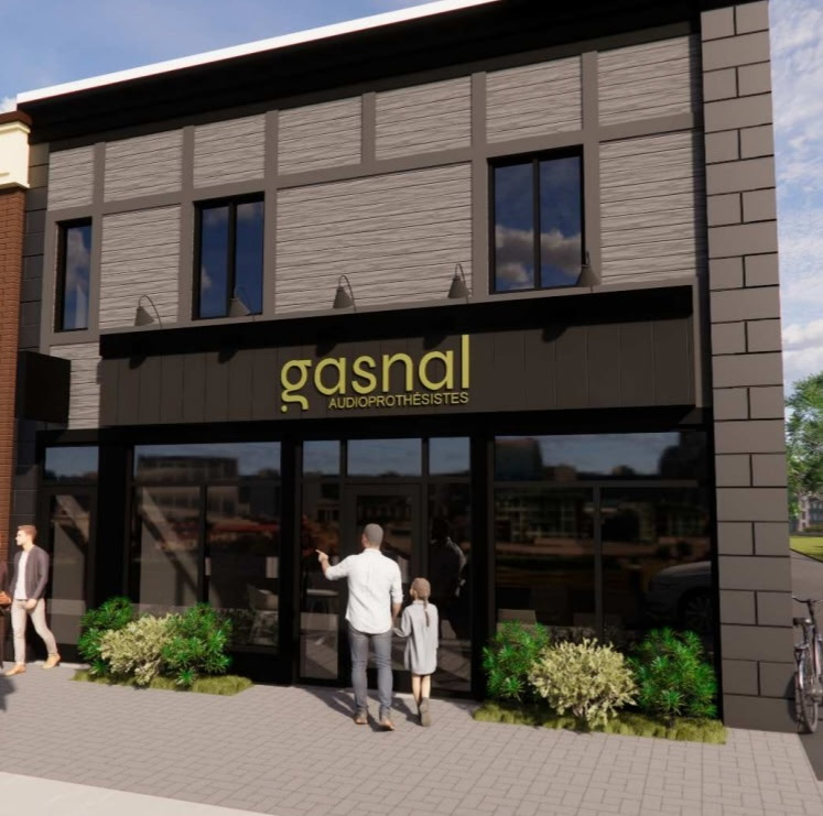 Façade d'un magasin Gasnal Audioprothésistes avec un homme et une enfant entrant par la porte vitrée.