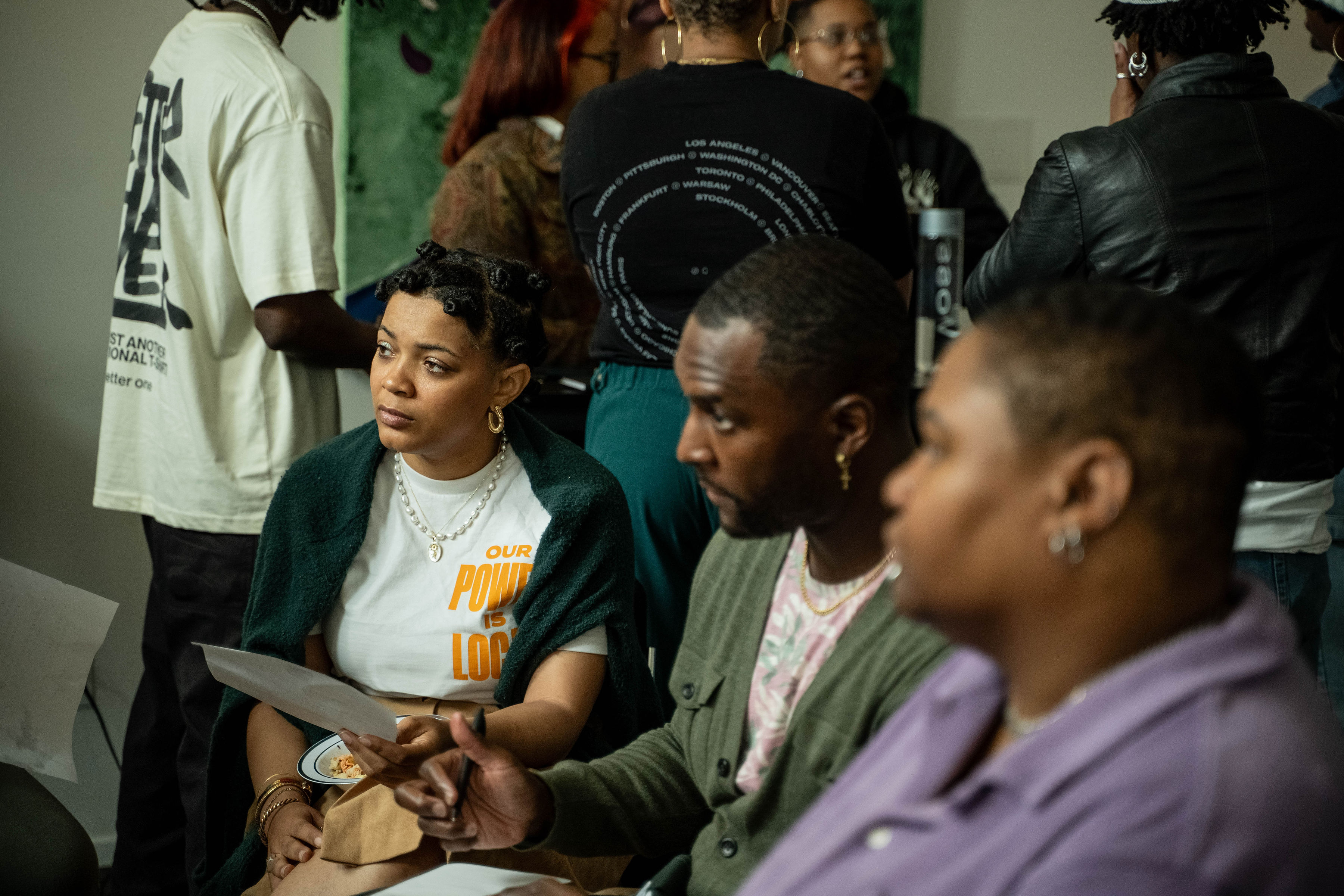 Three Black young adults at a gathering having a serious conversation and looking focused. 