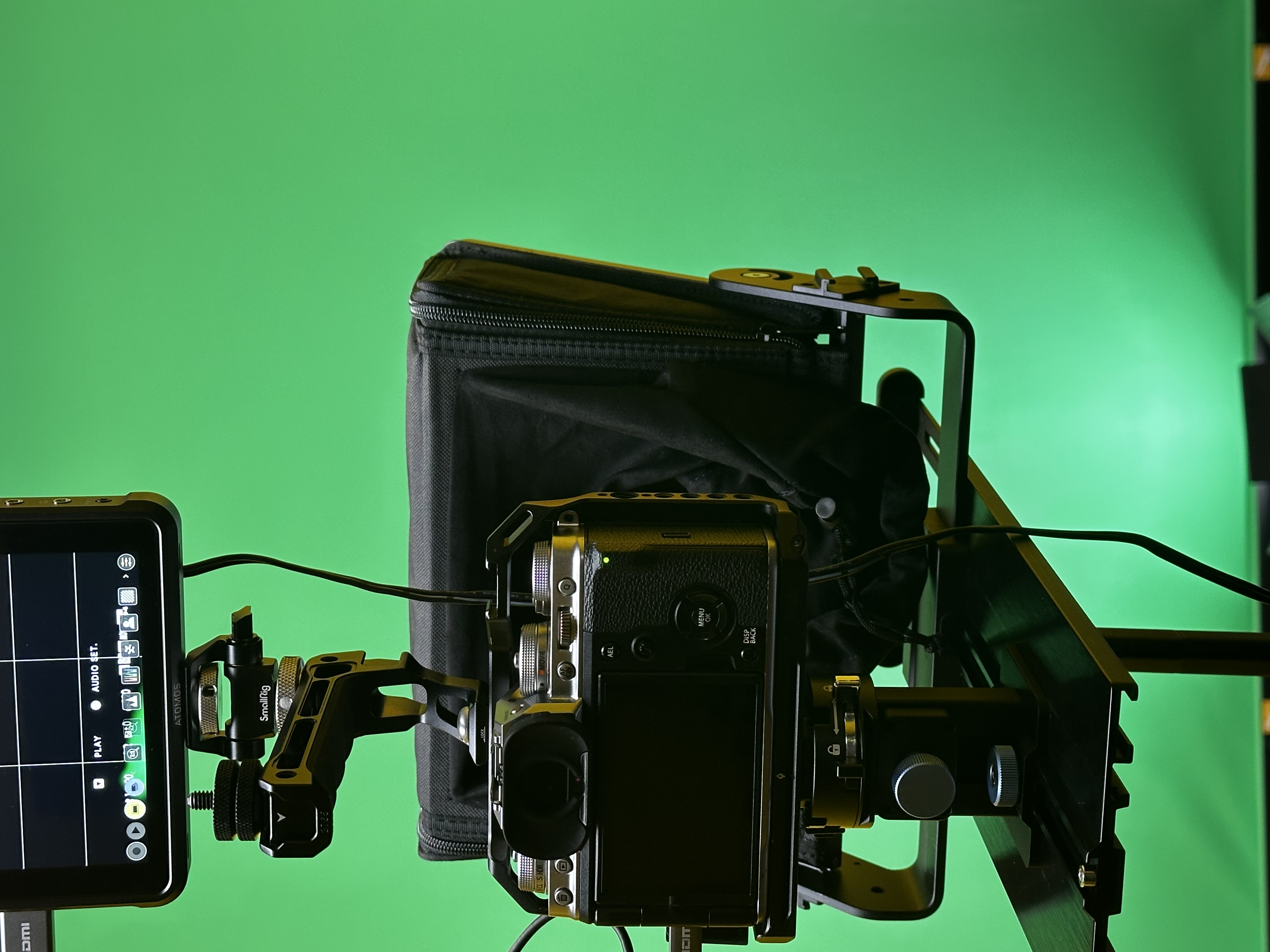 Photograph of a camera standing front of a greenscreen background
