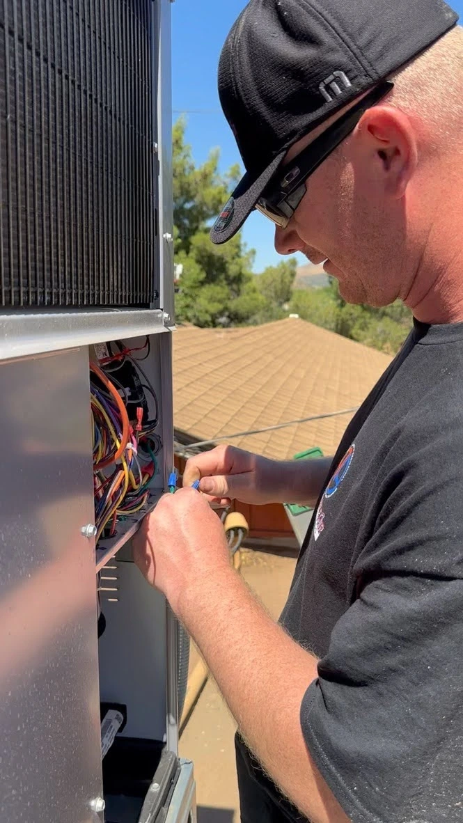 Technician in black cap working on electrical panel outdoors