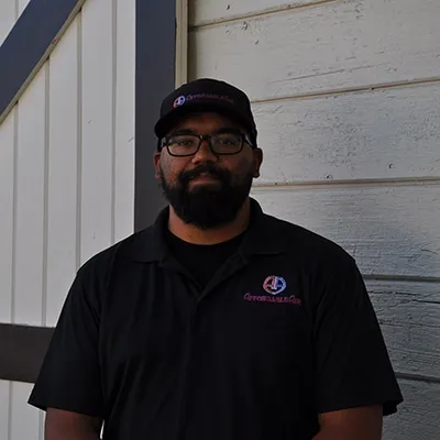 Person in black shirt and cap standing against white wall