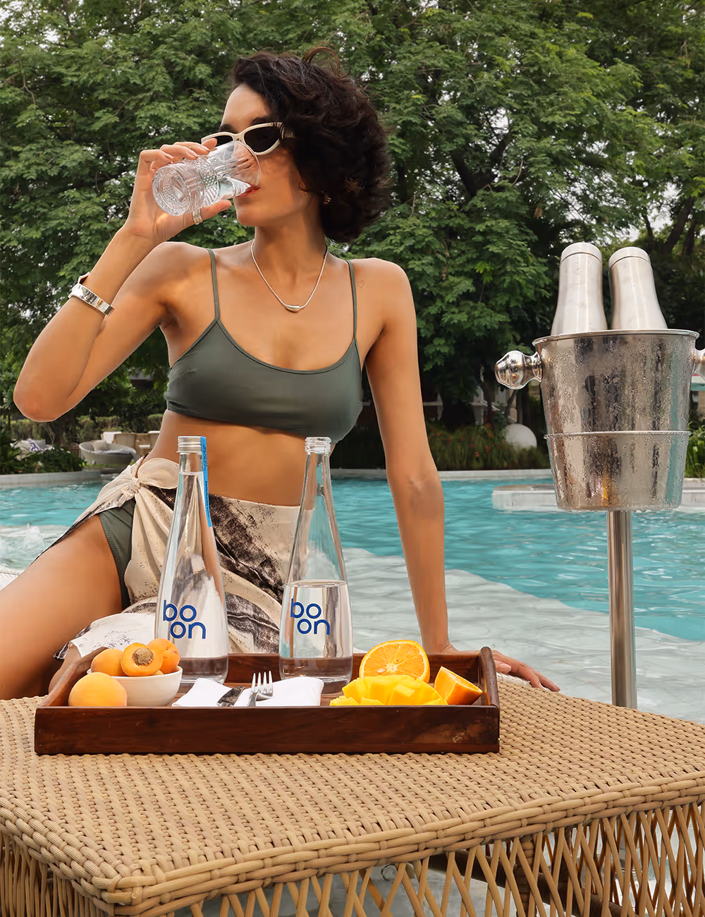 A lady drinking boon water beside a swimming pool