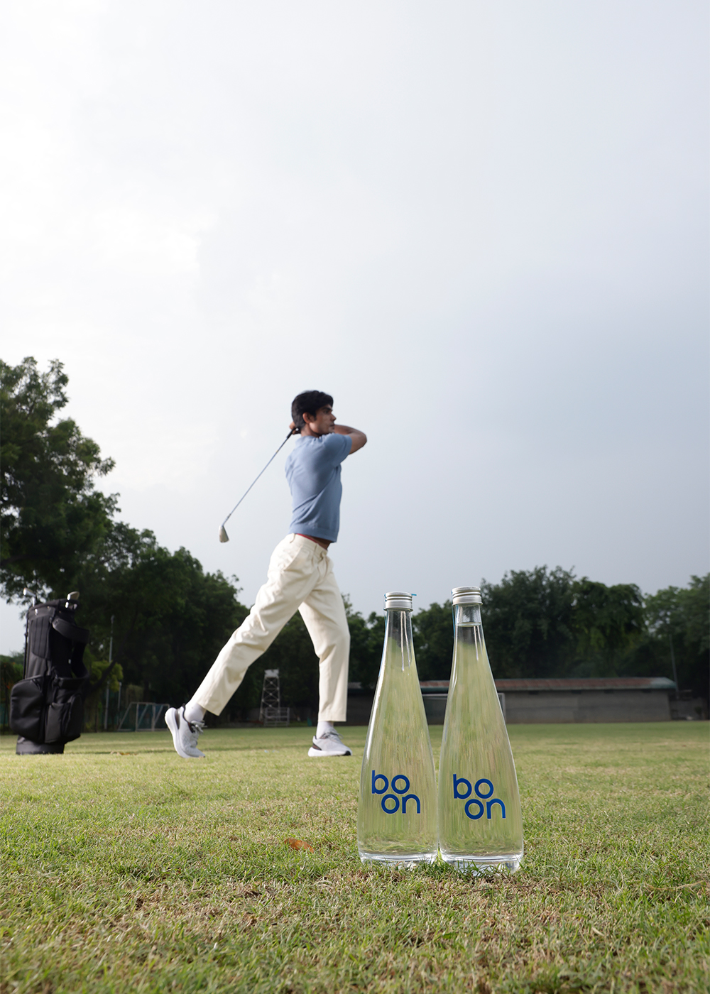 Two bottles of boon with a golf player in the background