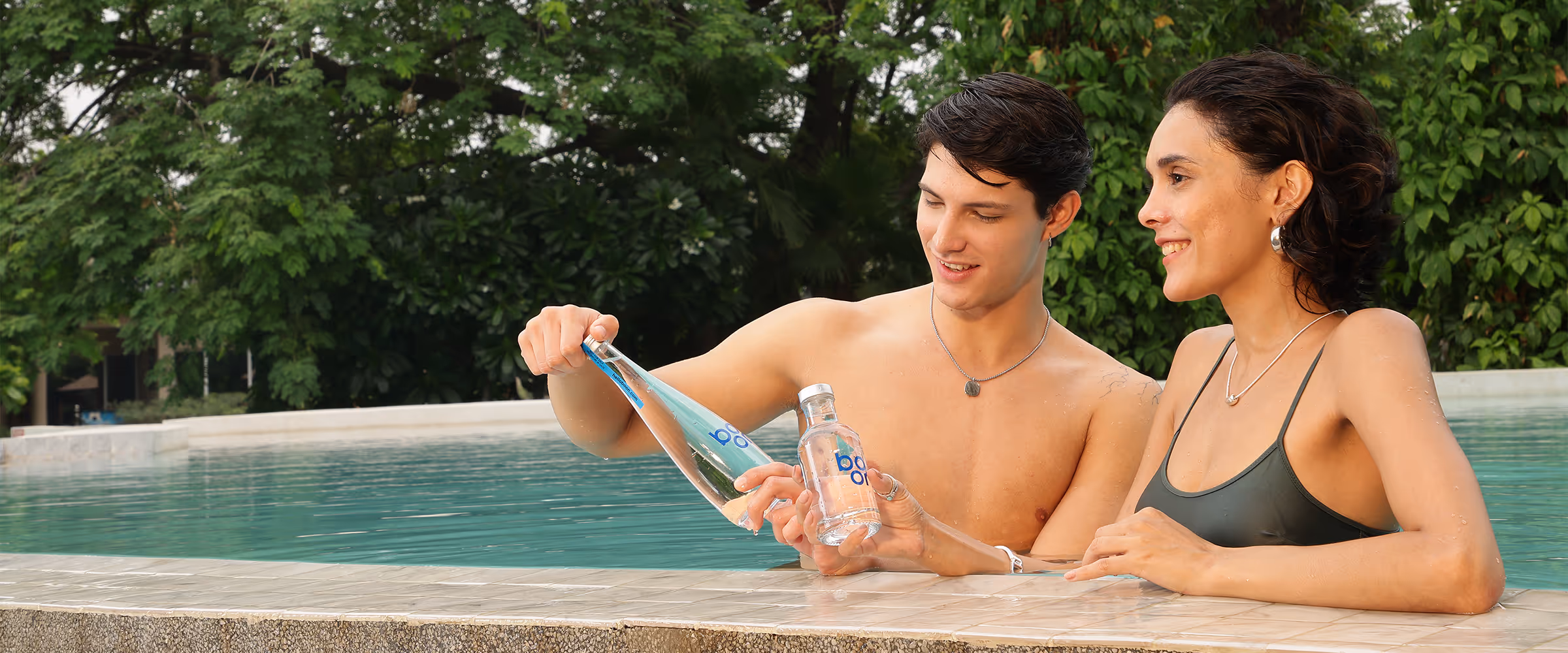 A couple in a swimming pool with boon water bottles