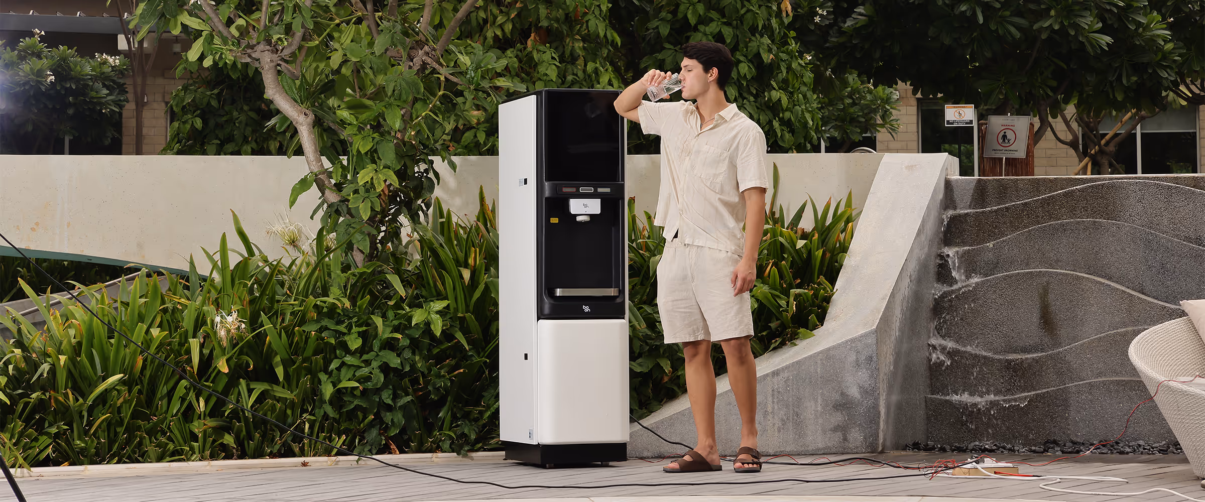 A man drinking water beside a boon water purifier