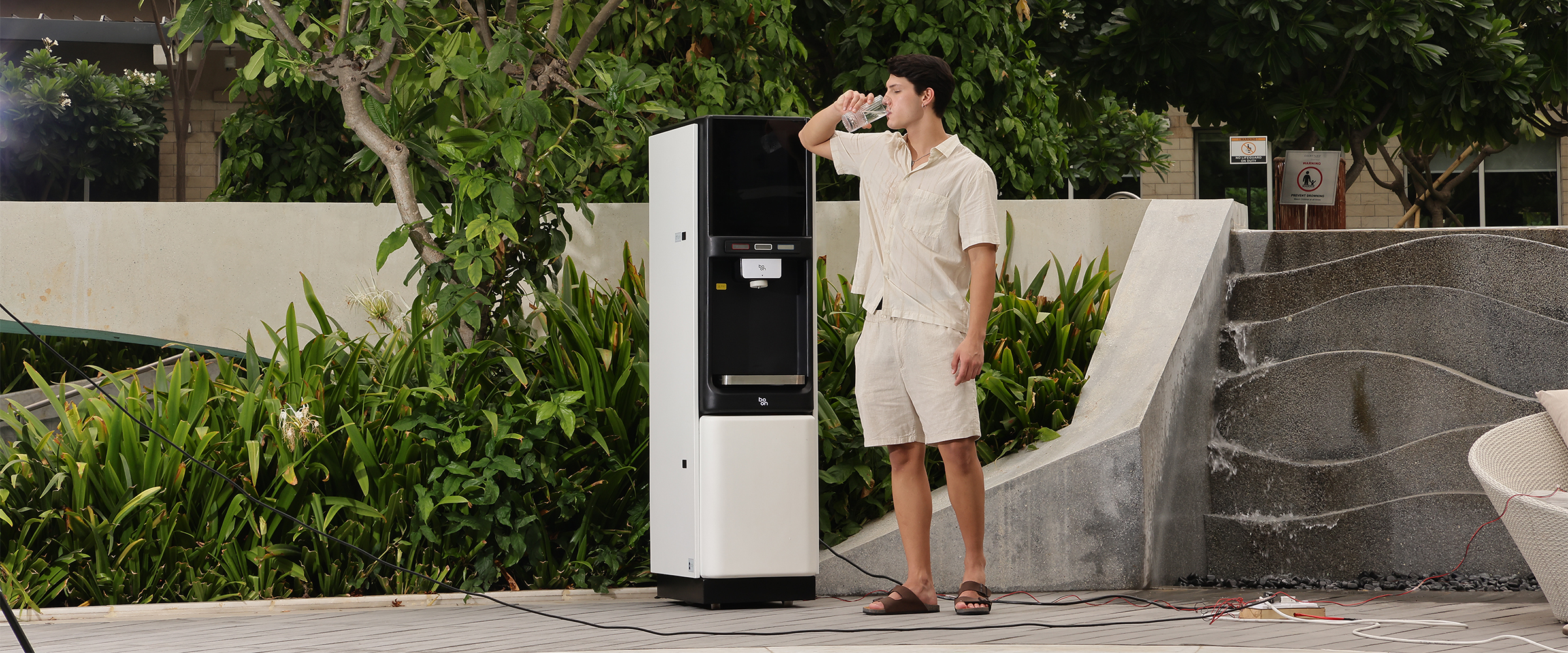 A man drinking water beside a boon water purifier