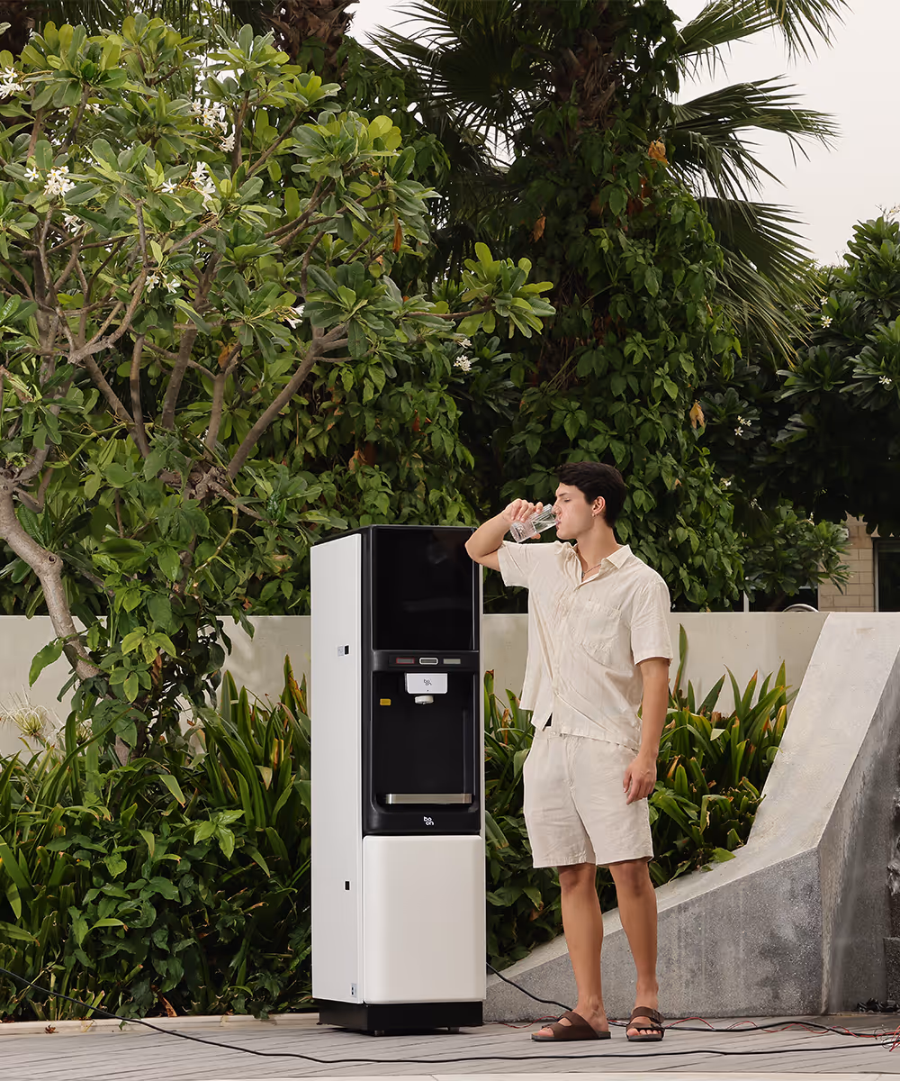 A man drinking water beside a boon water purifier