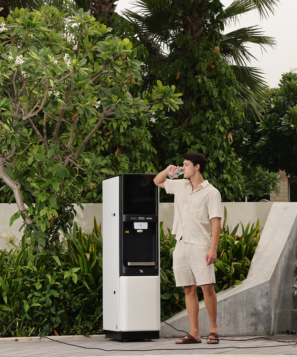 A man drinking water beside a boon water purifier