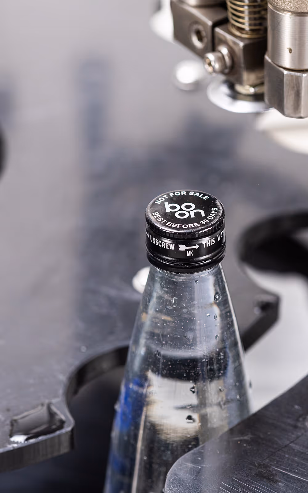 Closeup of a boon bottle in a capping machine
