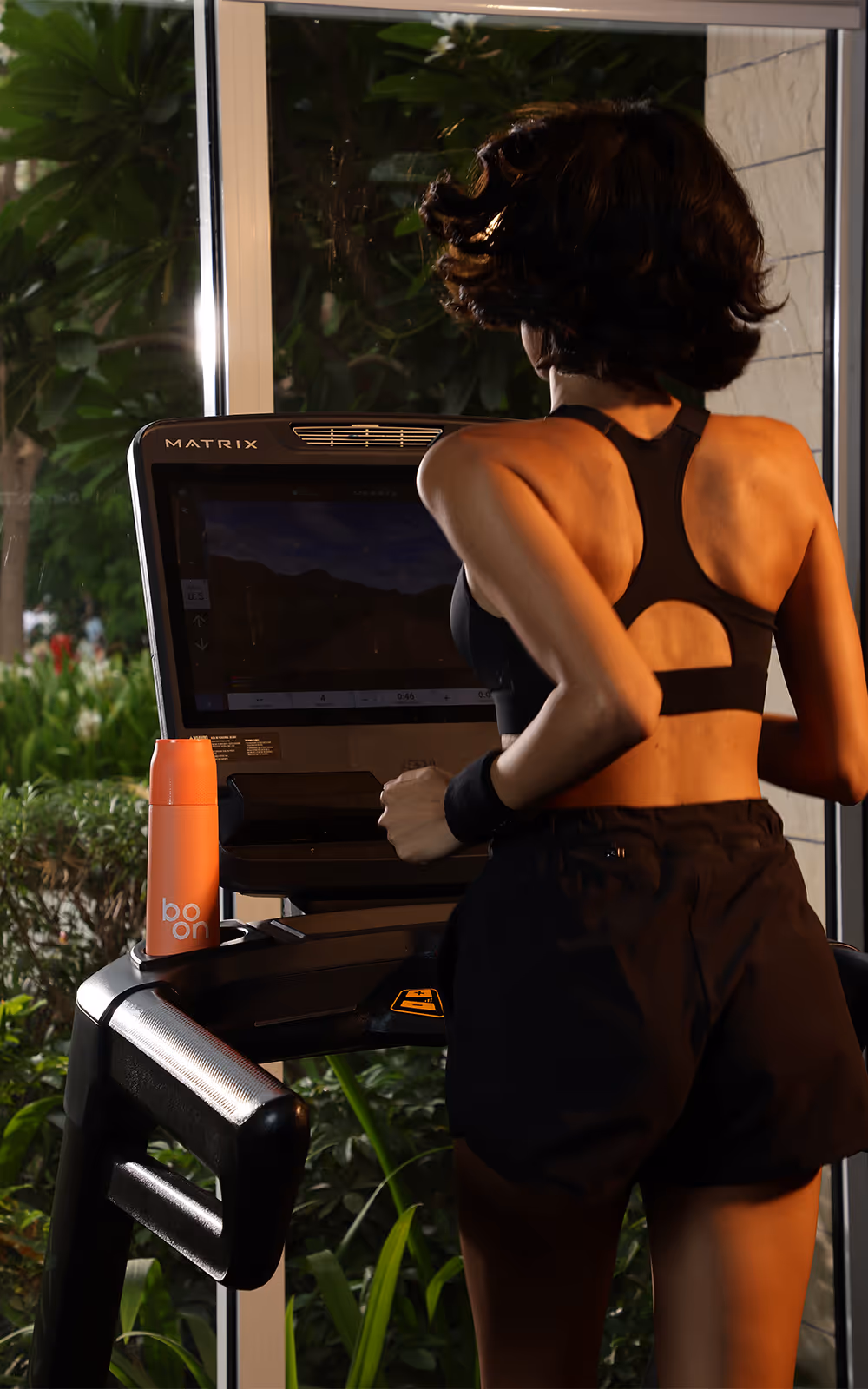 A lady on a treadmill with a boon waterbottle beside her