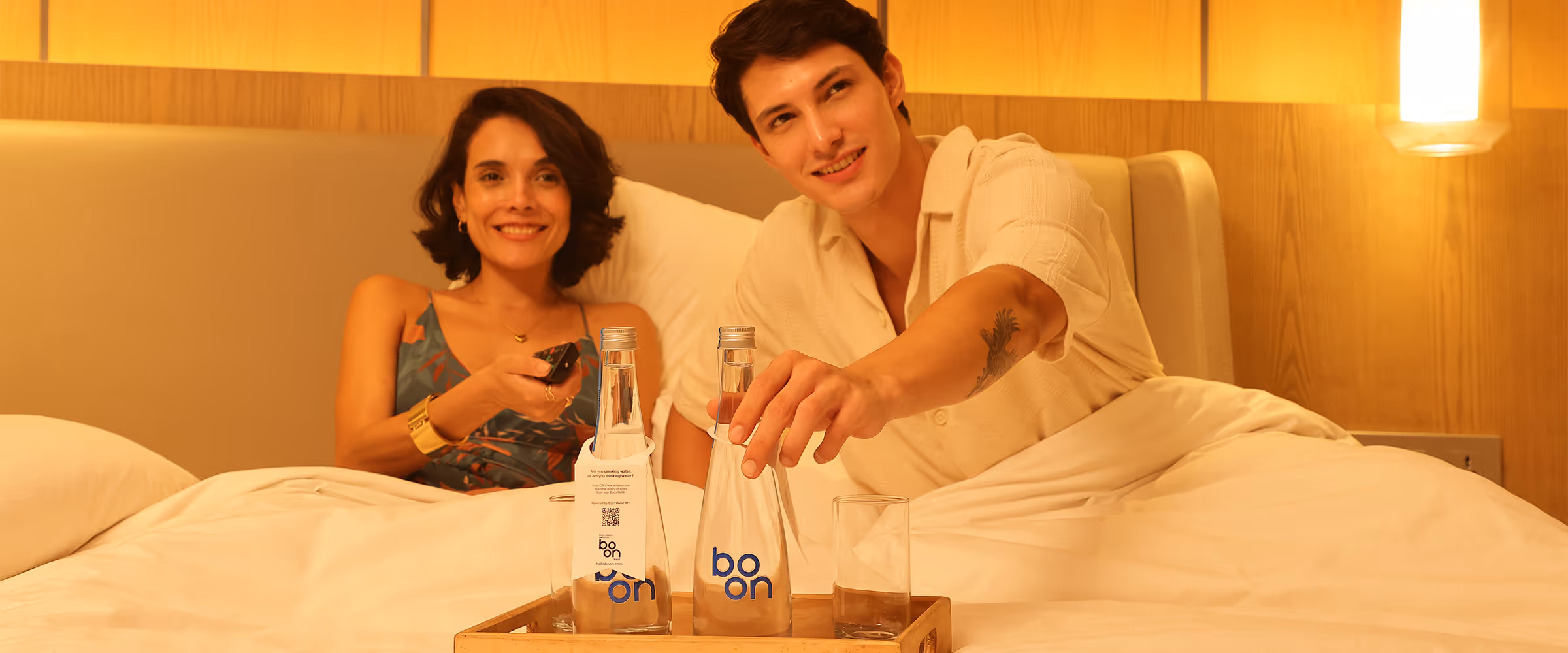 A happy couple in bed with a tray of boon bottles