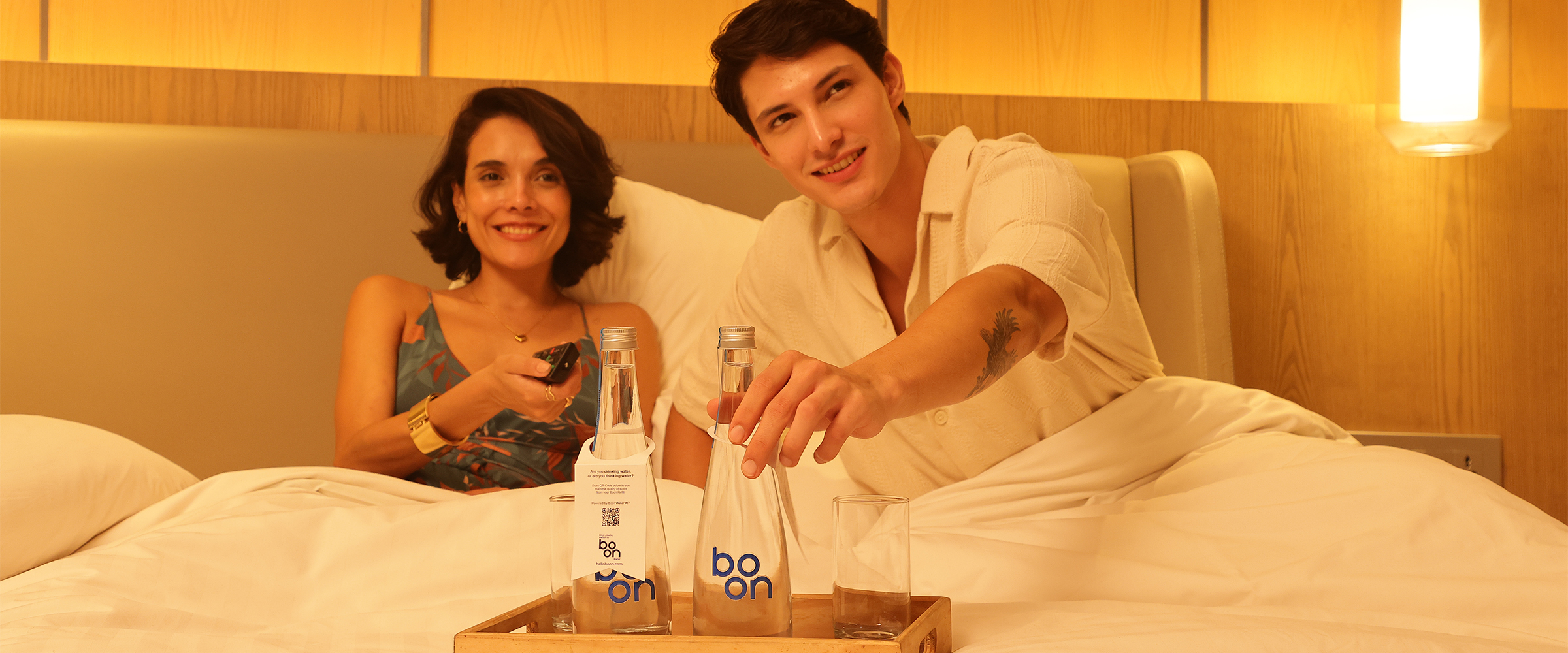 A happy couple in bed with a tray of boon bottles