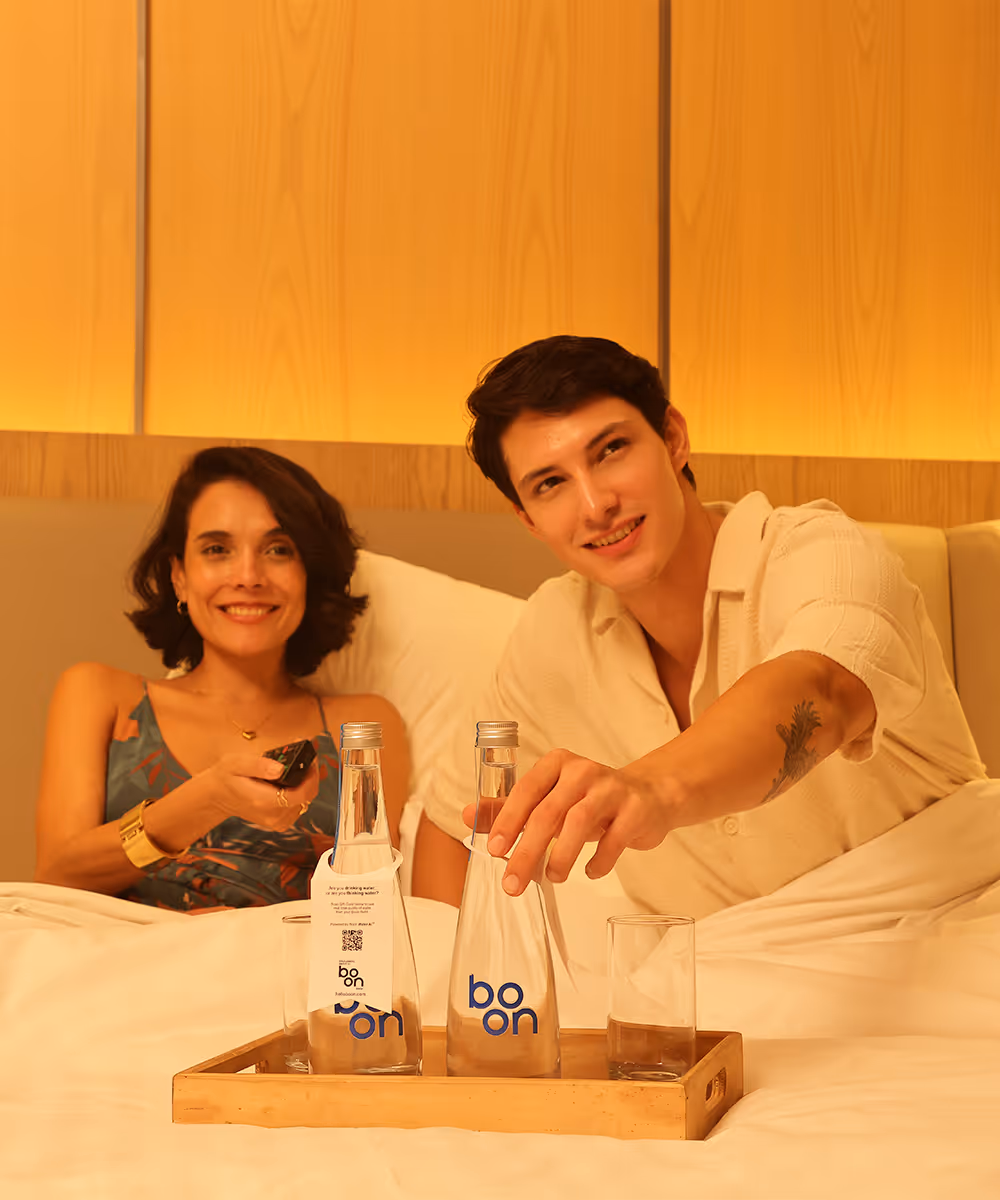 A happy couple in bed with a tray of boon bottles