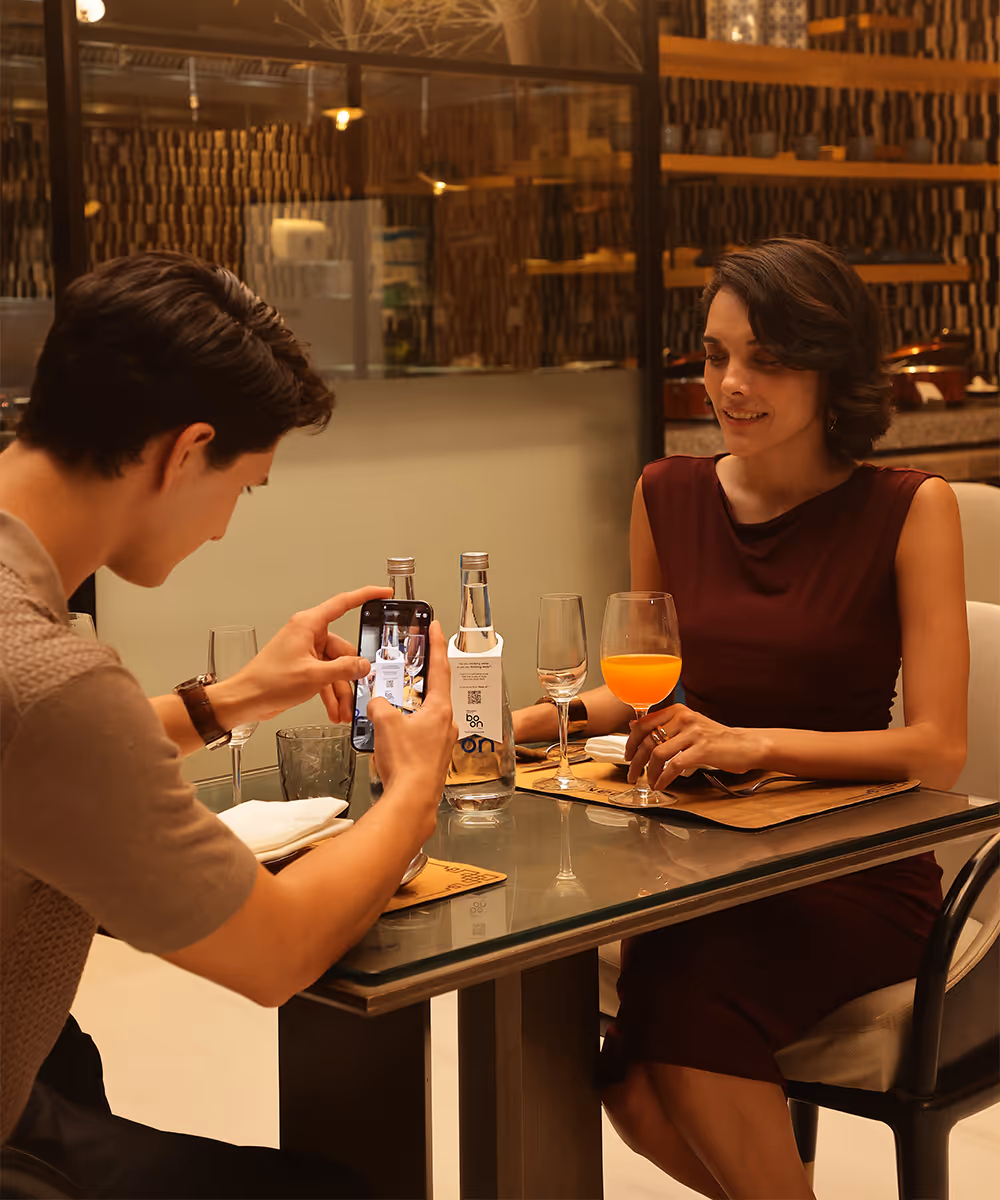 A couple in a restaurant with boon water bottles on the table
