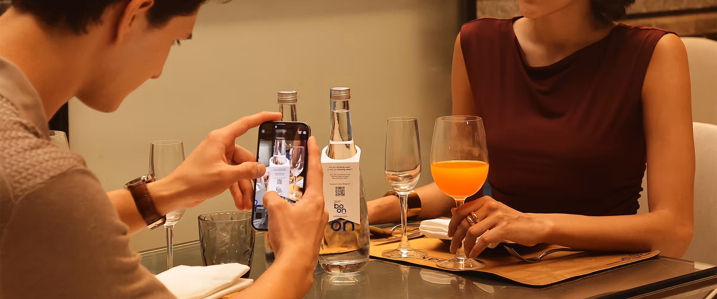 A couple in a restaurant with boon water bottles on the table