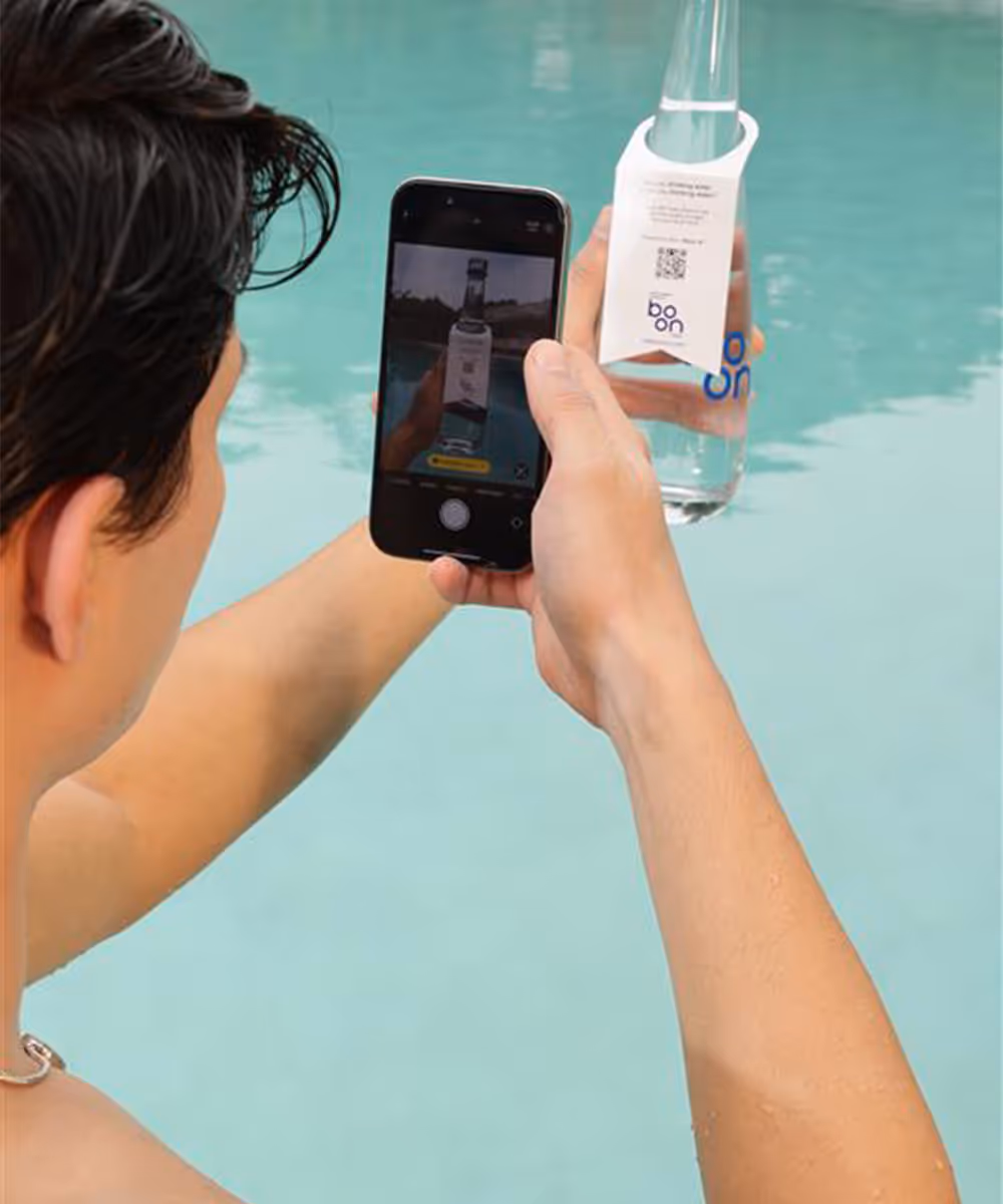 A man taking a picture of the boon water bottle 