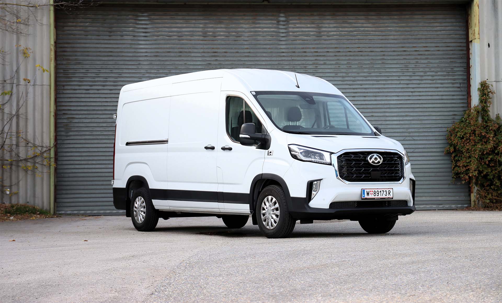 Weißer MAXUS DELIVER 9 Diesel vor einem Garagentor