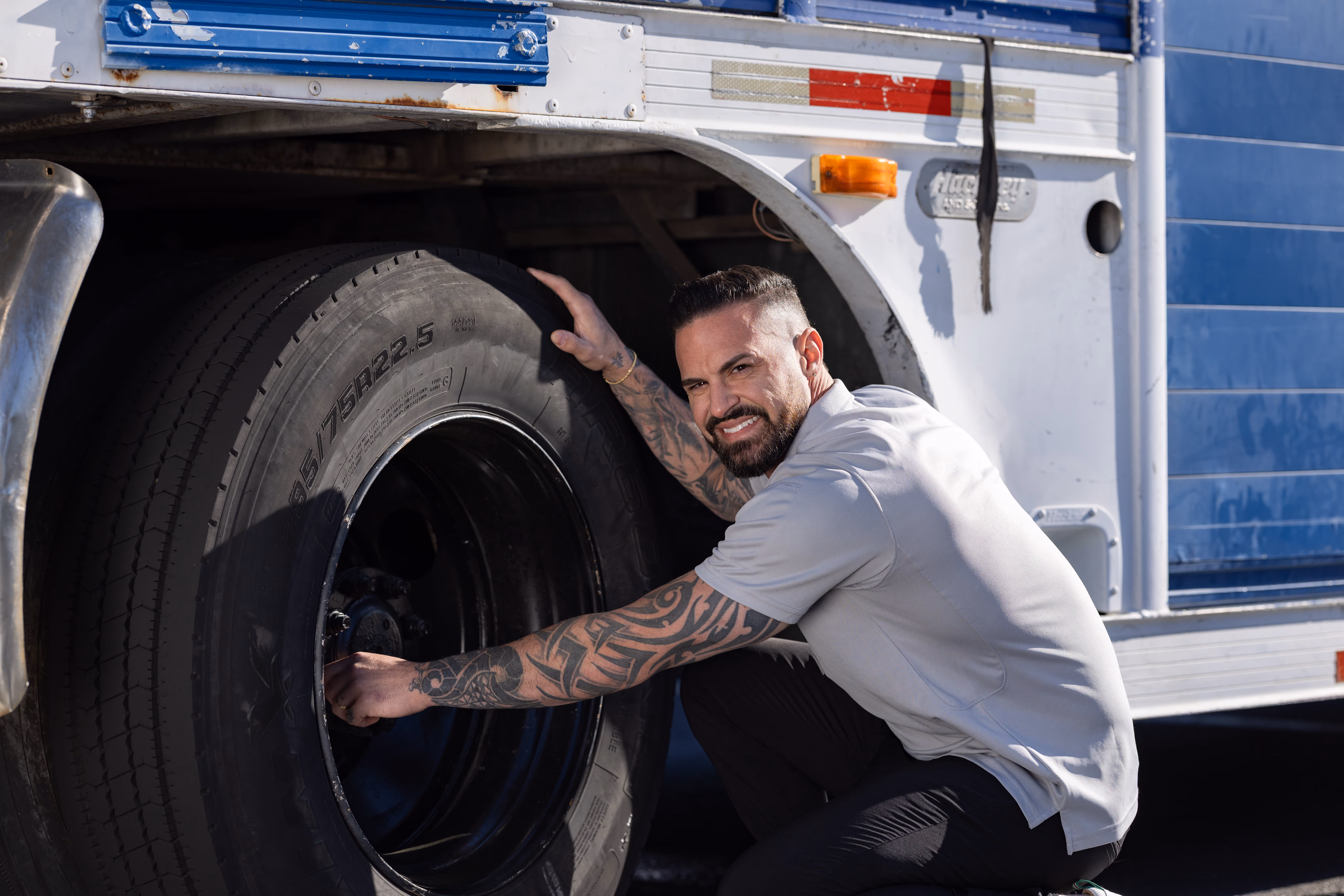 Man holding a truck tire and inspecting it