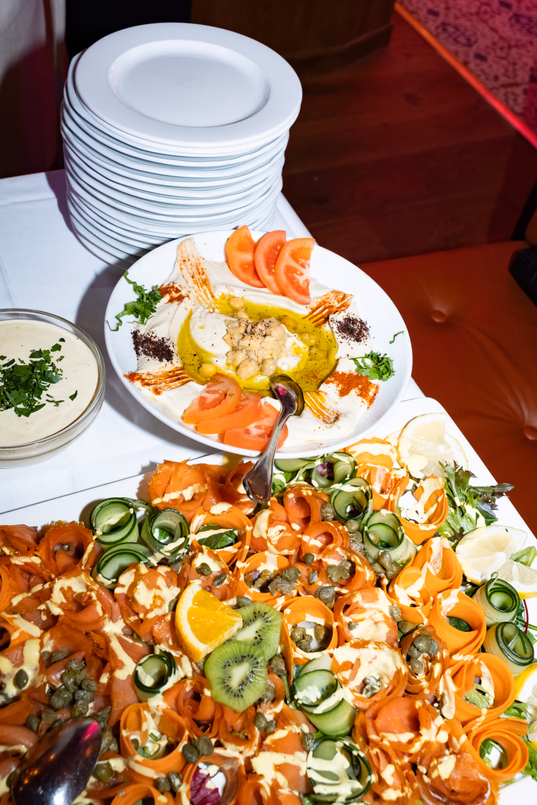 Tapasbuffet hos Riviera Restaurant i Oslo med kremet hummus, fersk laks, kapers, agurk og sitrusfrukter, servert som cateringmat.
