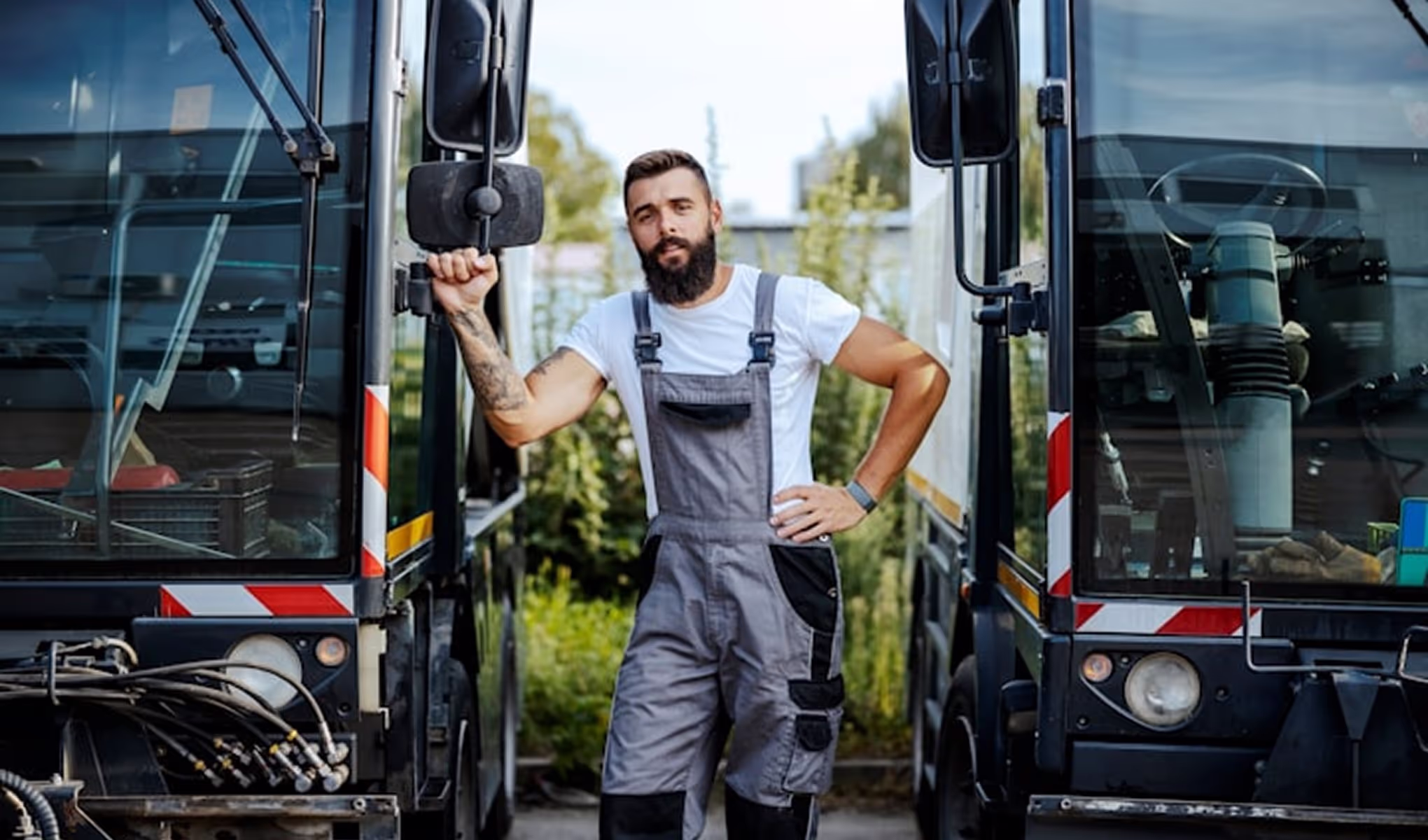 A man in overalls standing in front of a bus.