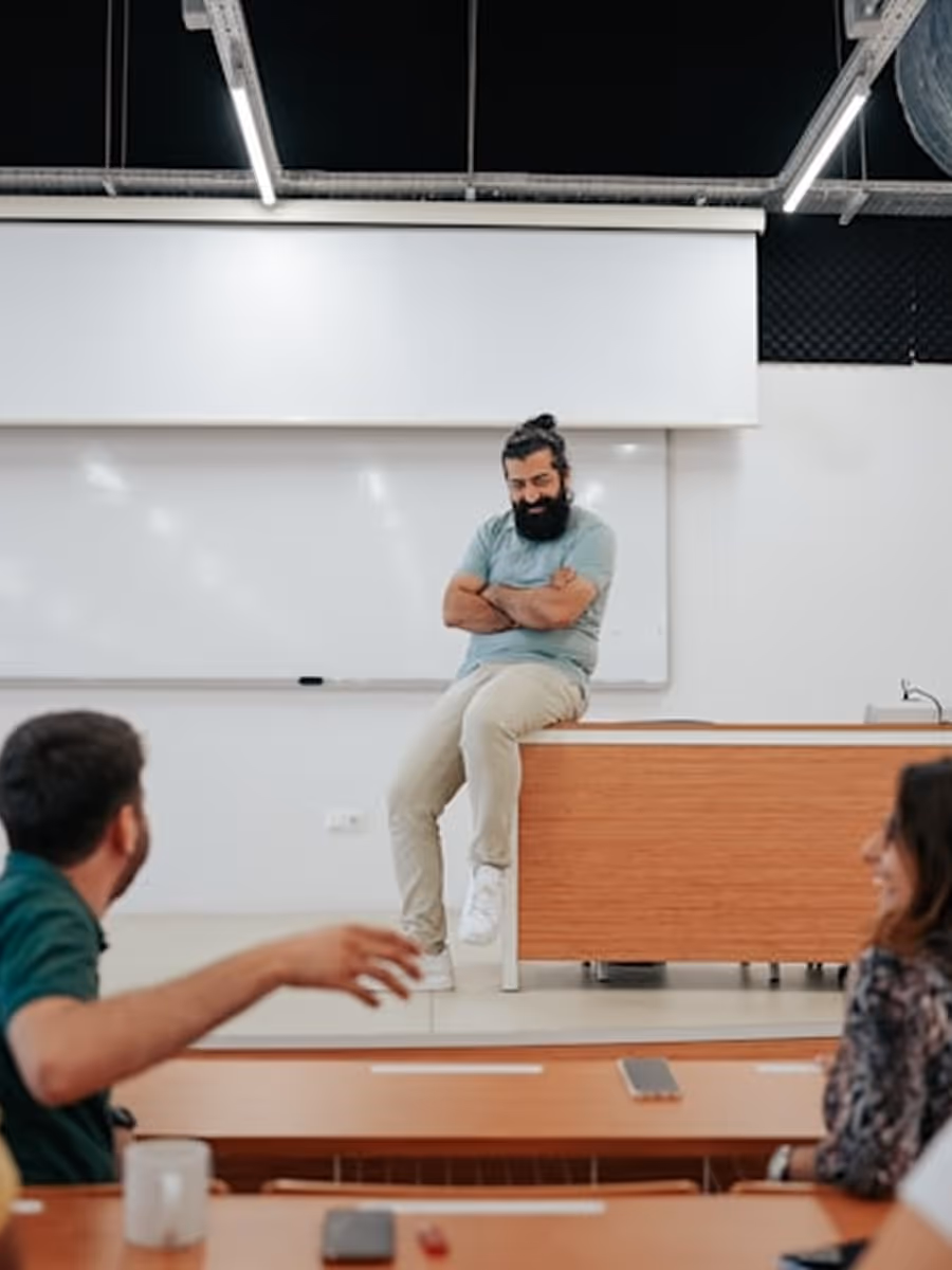 A man sitting on a desk in front of a group of people.