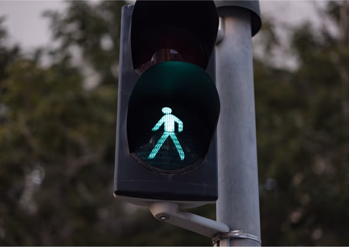 A traffic light with a green pedestrian sign on it.