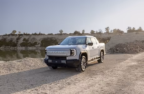 Silberner, vollelektrischer MAXUS eTERRON 9 Pick-up mit serienmäßigem Allradantrieb und großer Ladefläche in einer Kieslandschaft – kraftvoller Elektro-Pick-up für hohe Nutz- und Anhängelast."