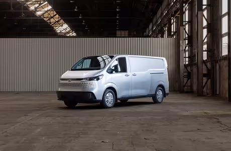 Neuer MAXUS DELIVER 7 in Silber, vollelektrischer Kastenwagen für urbanen und gewerblichen Einsatz, geparkt in einer Industriehalle – moderner Elektro-Transporter mit viel Laderaum.