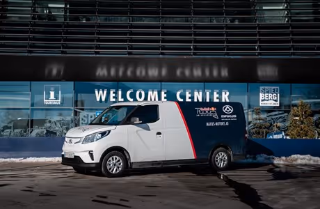 MAXUS eDELIVER 3 Elektro-Kleintransporter im Einsatz am Red Bull Ring, vor dem Welcome Center geparkt – emissionsfreier Transporter für flexible Einsätze abseits der Rennstrecke.