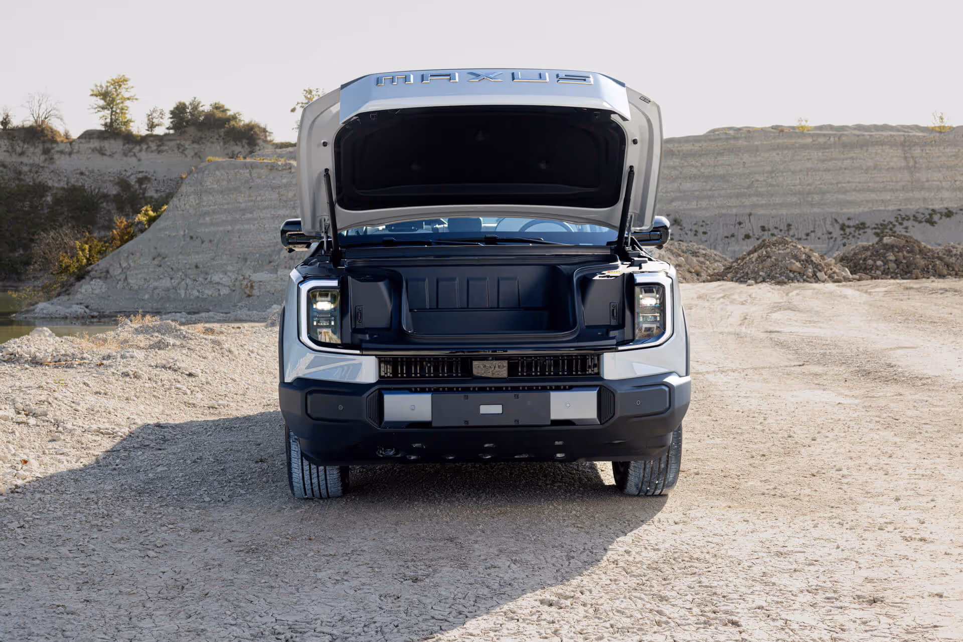 MAXUS eTERRON 9 Pick-up mit geöffnetem Frunk in Kieslandschaft – vollelektrischer Pick-up mit zusätzlichem Stauraum und Allradantrieb.