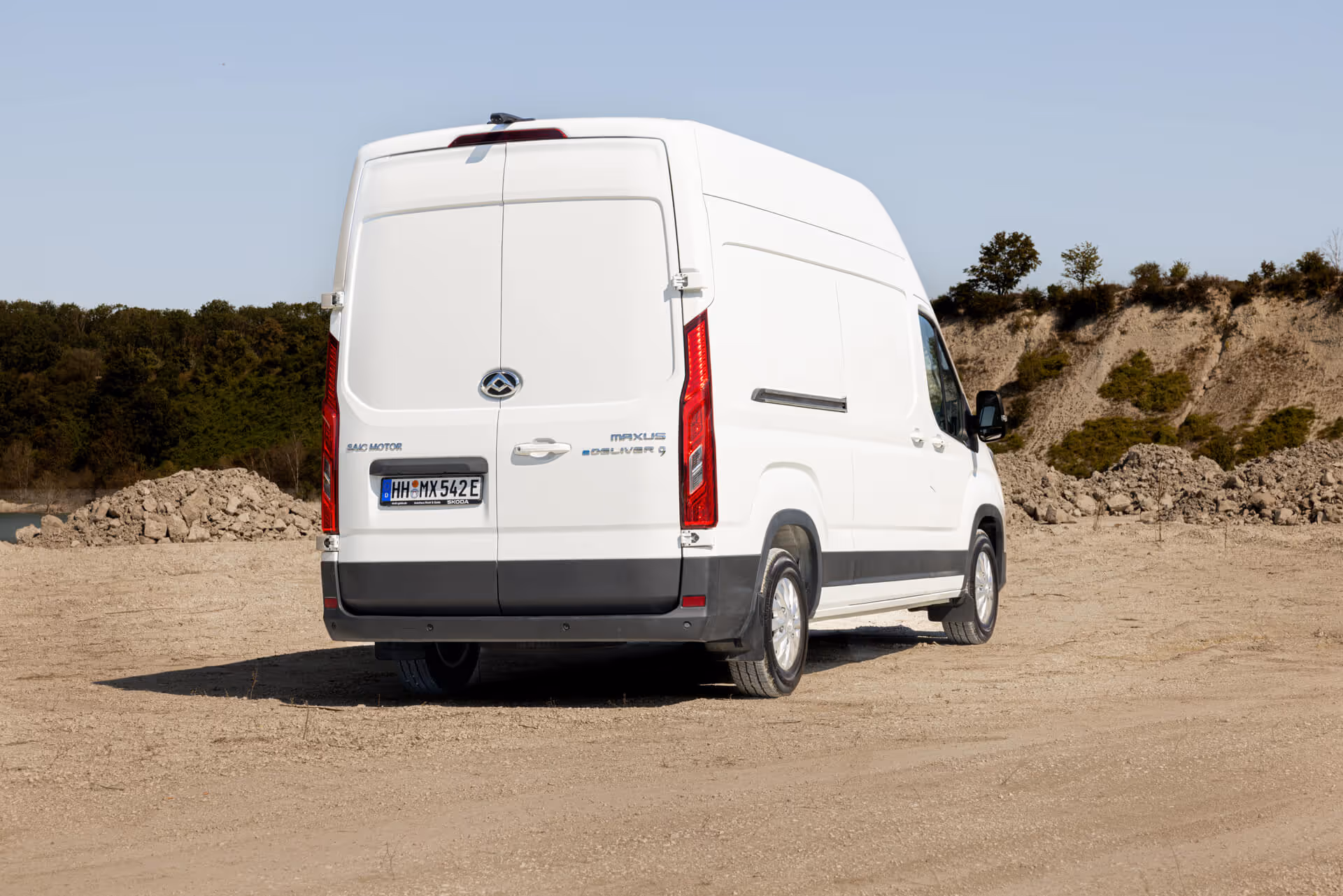 Heckansicht des weißen MAXUS eDELIVER 9 Elektro-Transporters in Kieslandschaft – vollelektrischer Kastenwagen mit hoher Nutzlast und großem Ladevolumen für emissionsfreie Transporte.