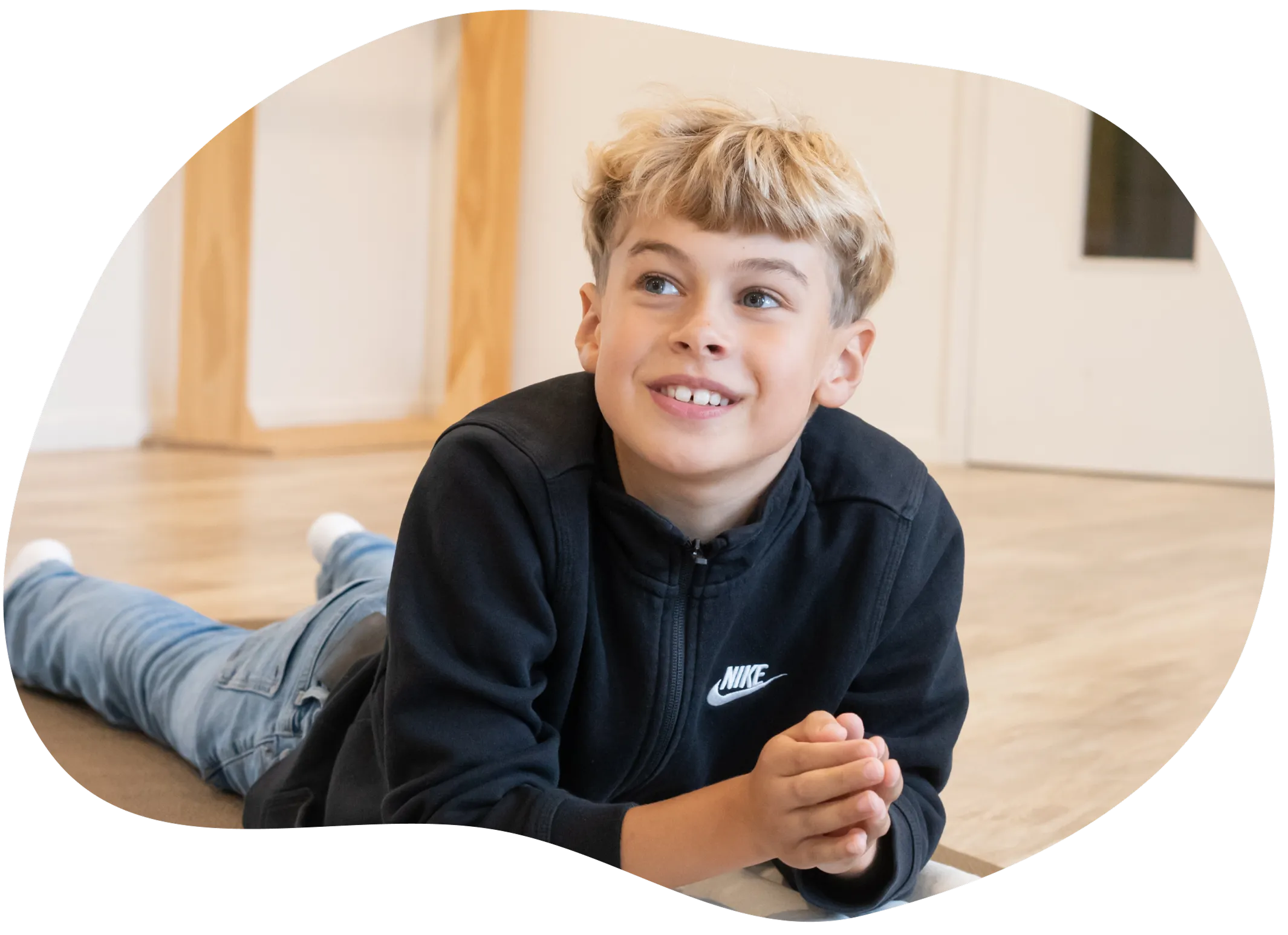 Blij jongentje die op de vloer ligt