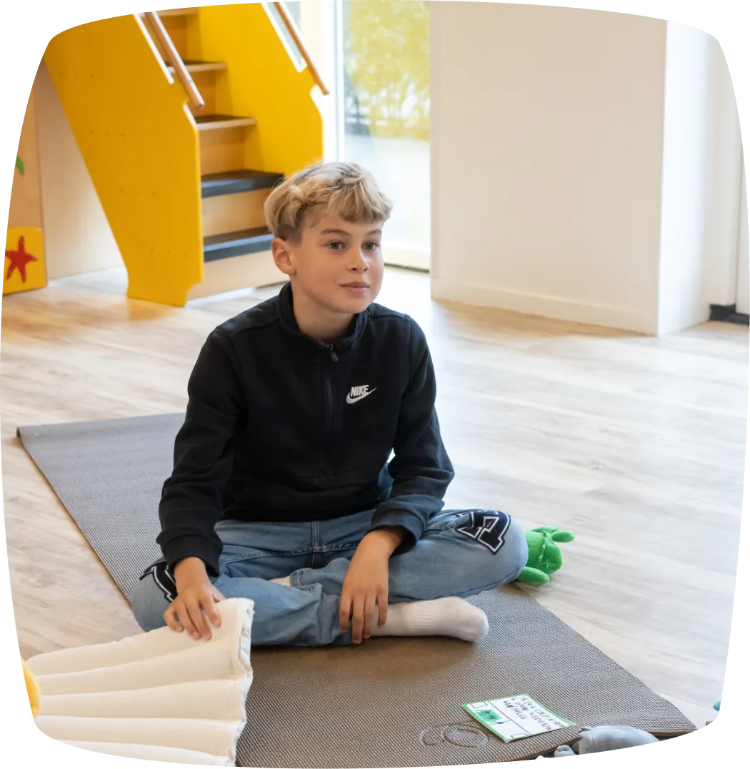 Een blonde jongentje op een yogamat